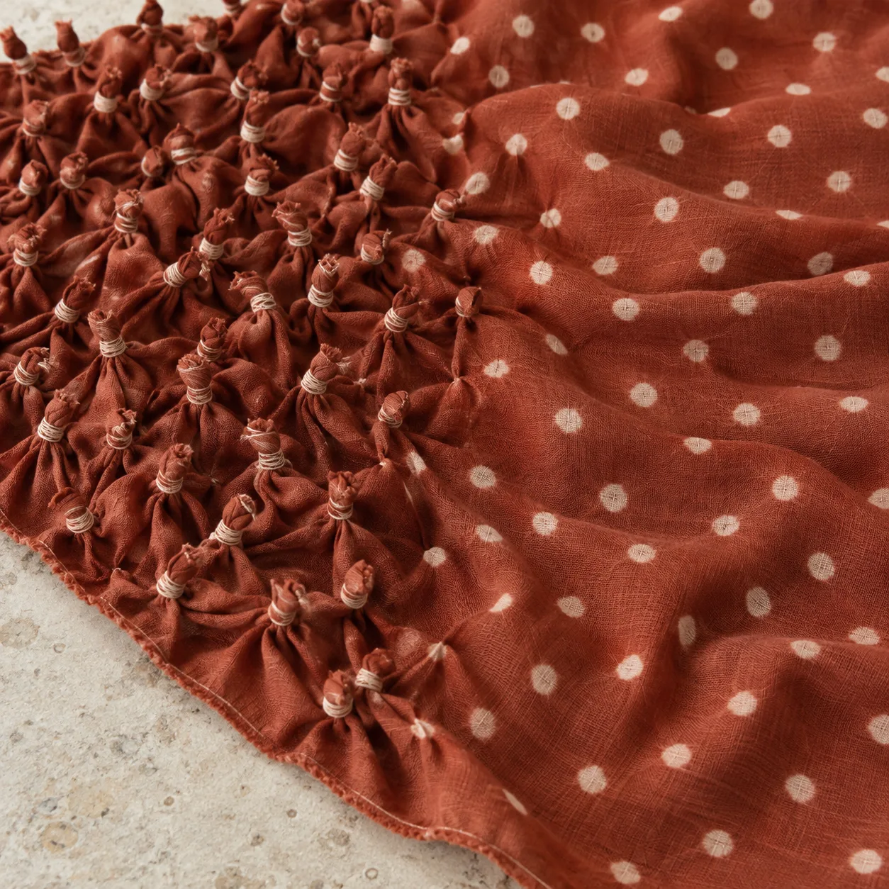 One rust-red cotton cloth with thread-bound points on the left and opened white dots on the right