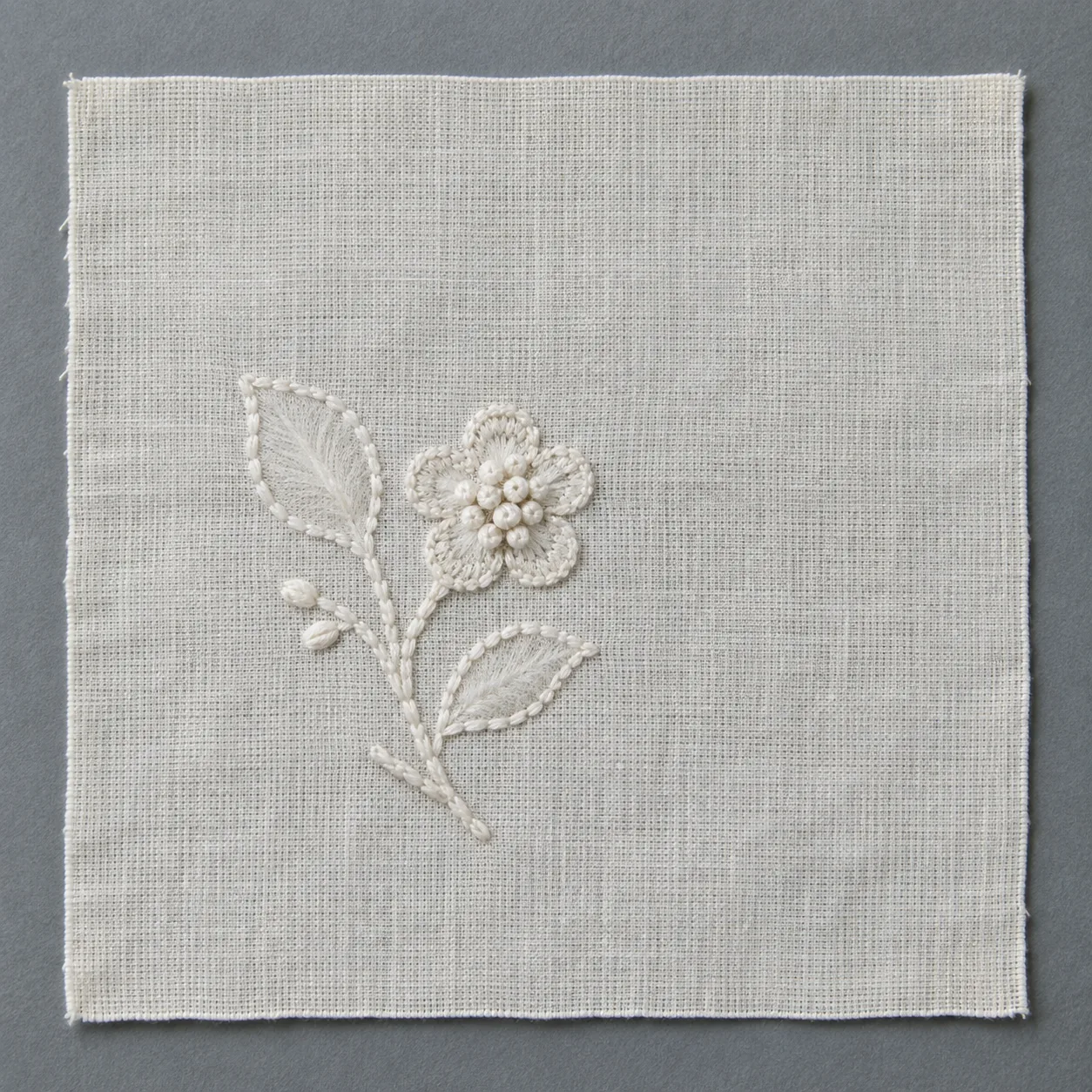White floral embroidery on fine cotton muslin, with outlined leaves, shaded interiors and raised knots