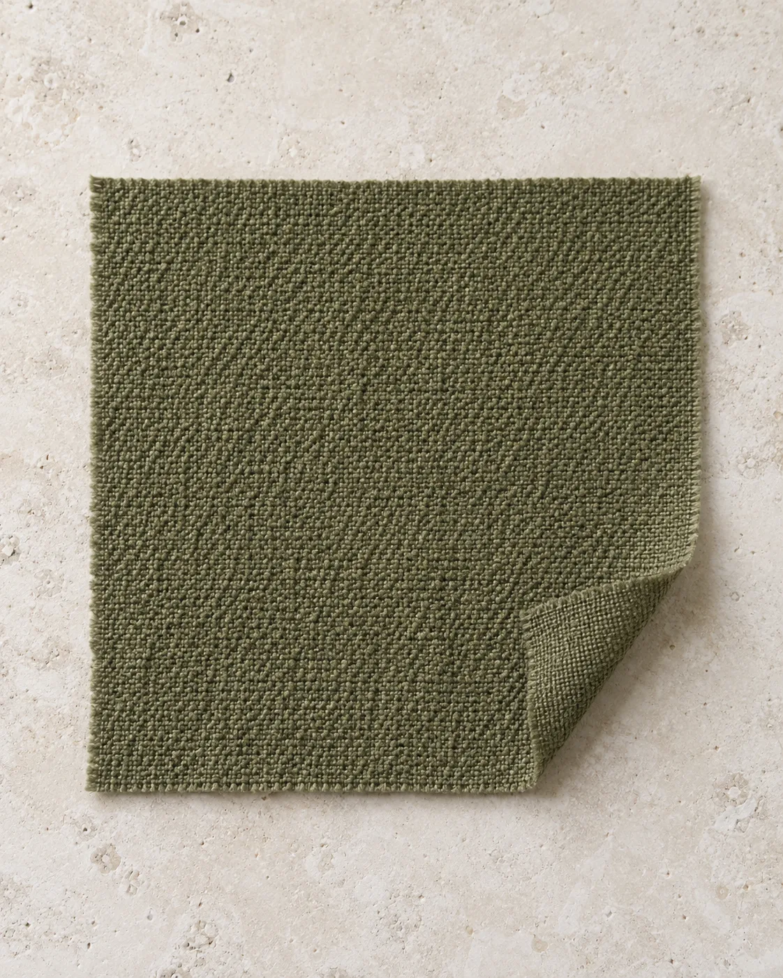 Olive crepe swatch on pale stone, with a pebbly surface and one corner folded back