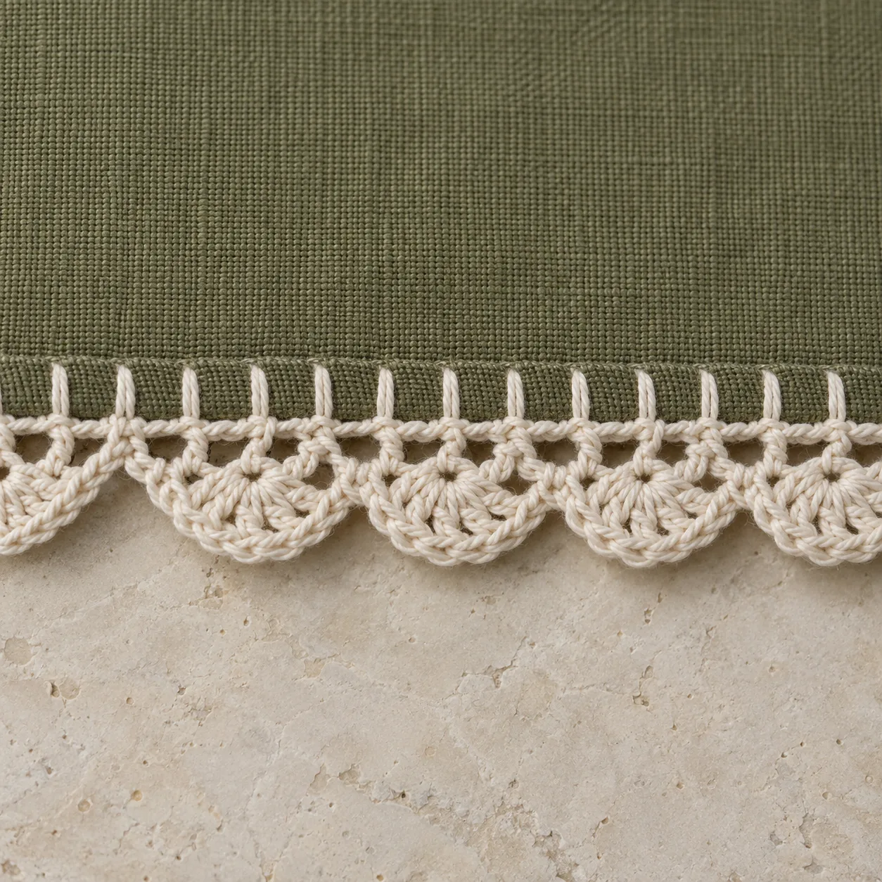 Ecru crochet scallops joined to blanket stitches along an olive woven fabric edge