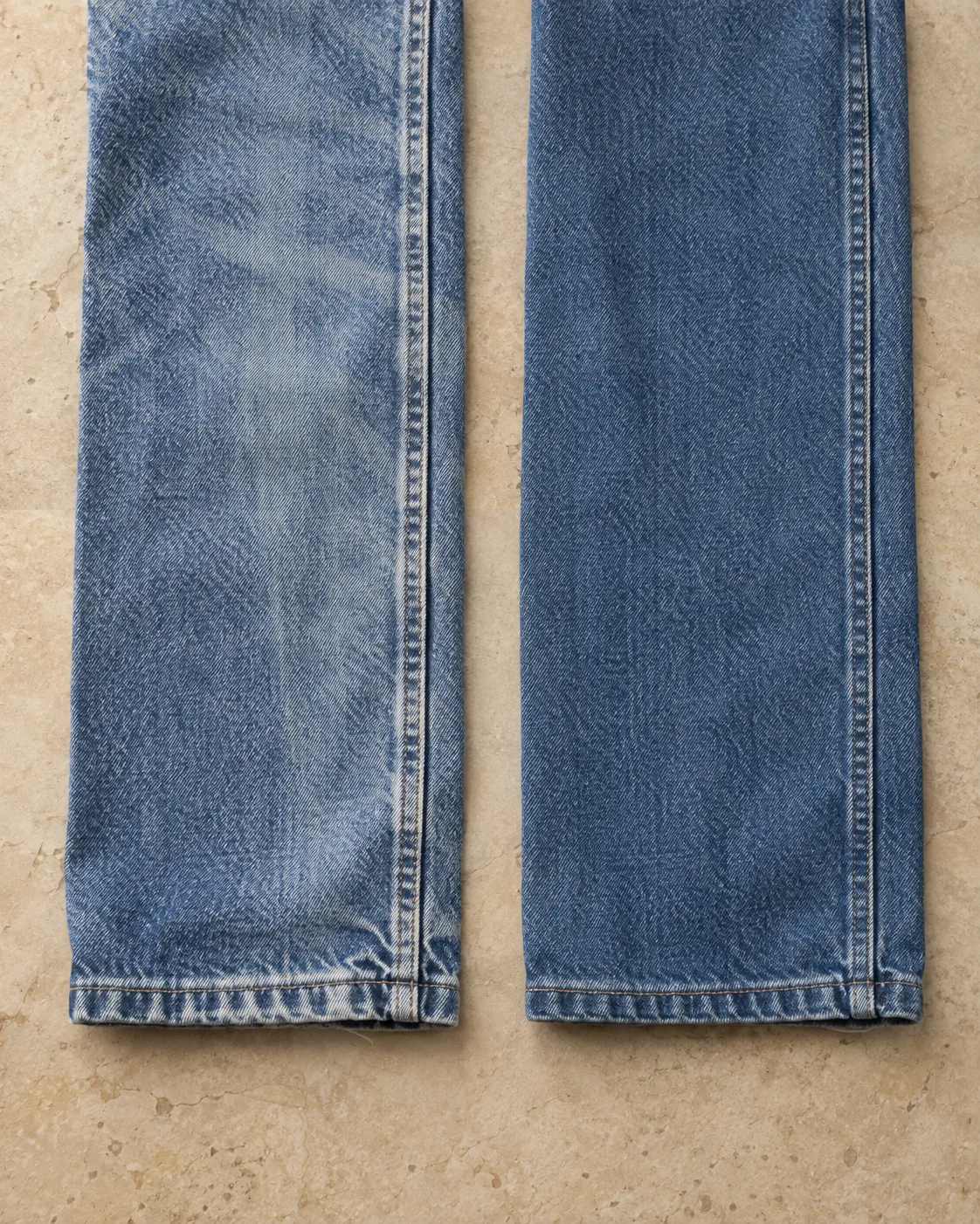 Two sewn denim lower-leg panels with seams and hems: stone wash on the left and enzyme wash on the right