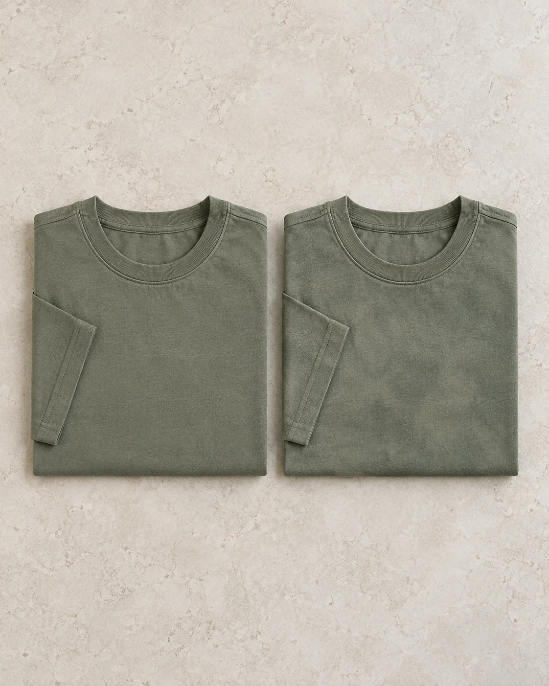 Two folded sage-olive cotton T-shirts, one evenly coloured and one with softly uneven colour