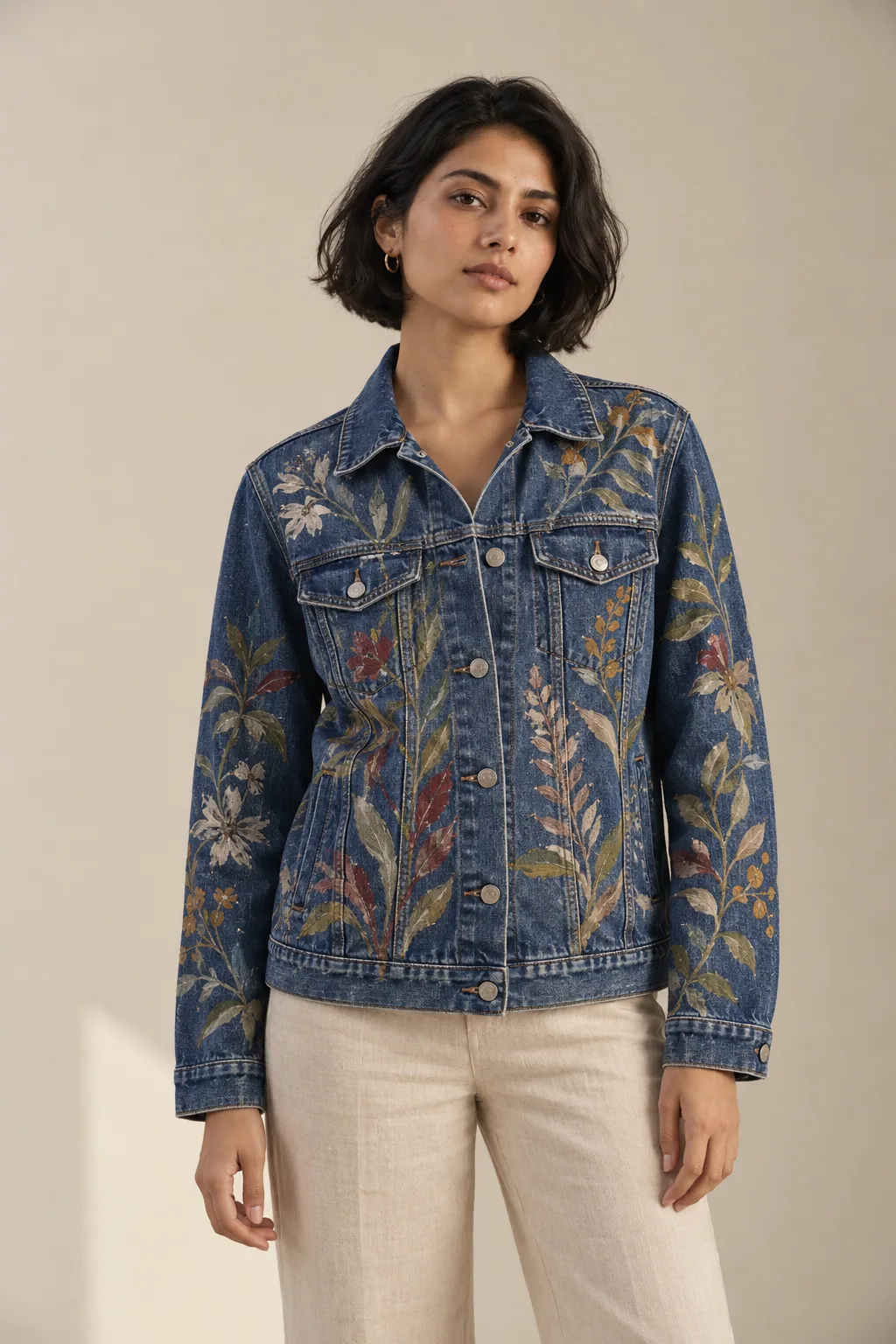 Blue denim jacket painted with flowers and leaves across the front and sleeves