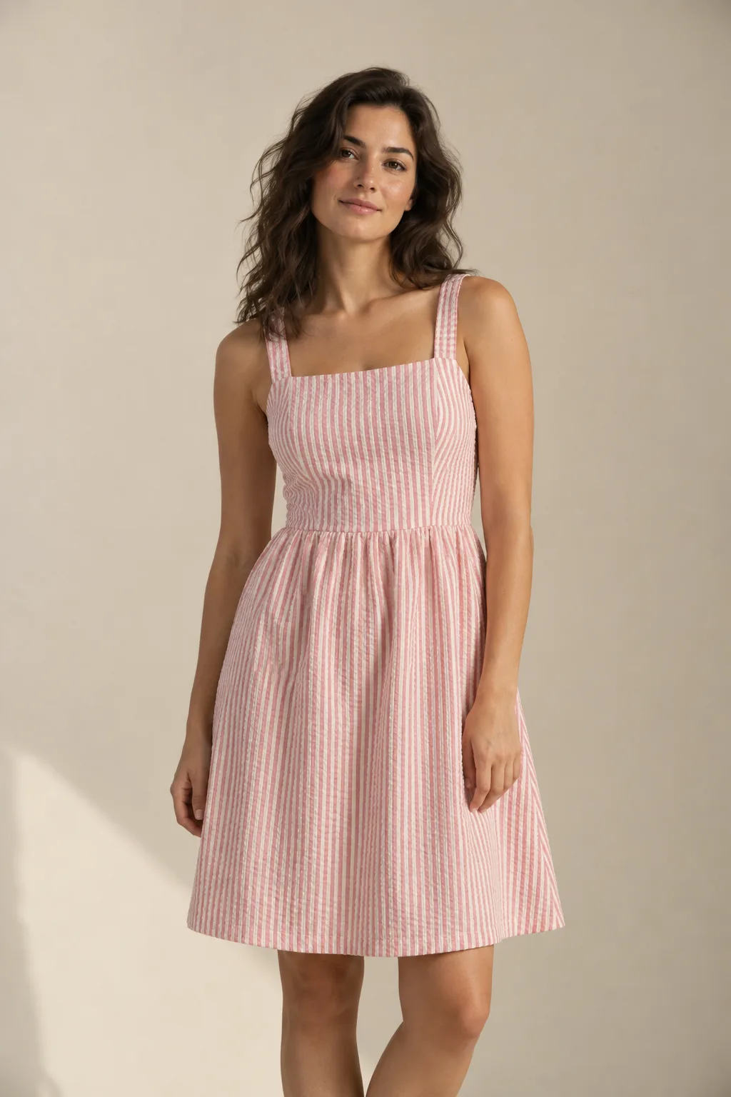 Woman wearing a pink and white striped seersucker sundress with a gathered skirt