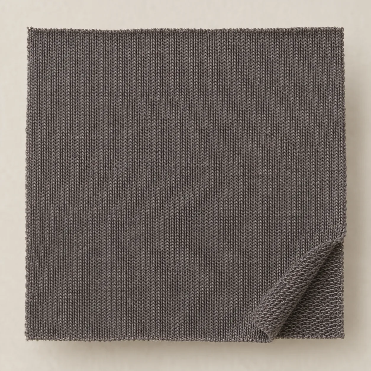 Grey single-jersey fabric with V-shaped face stitches and reverse loops at a folded corner