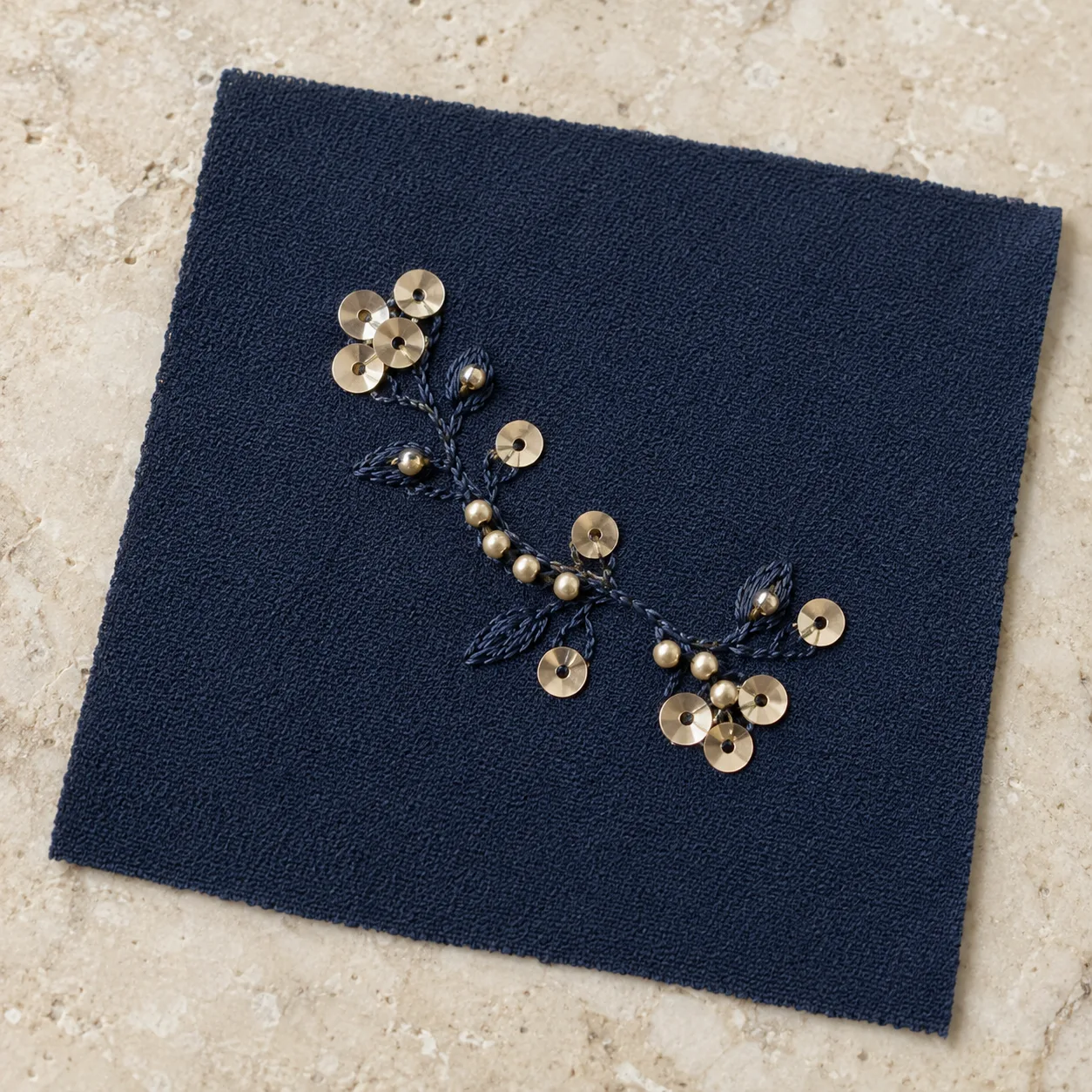 Champagne sequin discs and rounded beads in navy chain-stitch embroidery on navy crepe