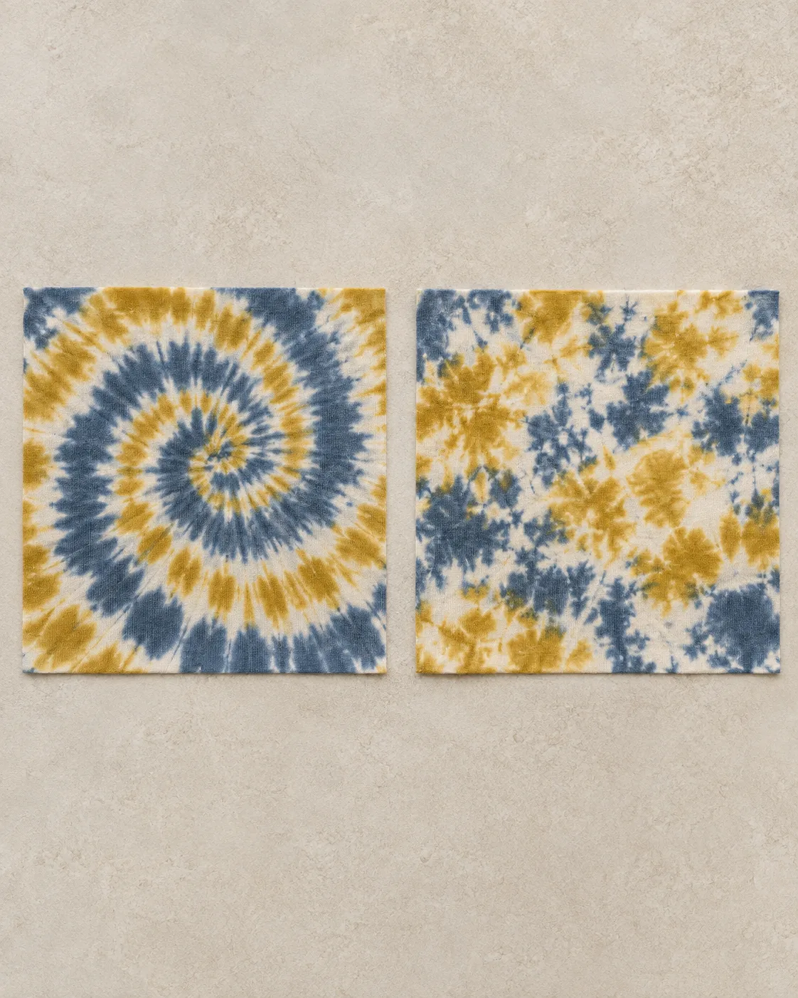 Two cotton jersey squares in slate-blue, mustard and ecru: spiral tie-dye on the left and mottled crumple tie-dye on the right