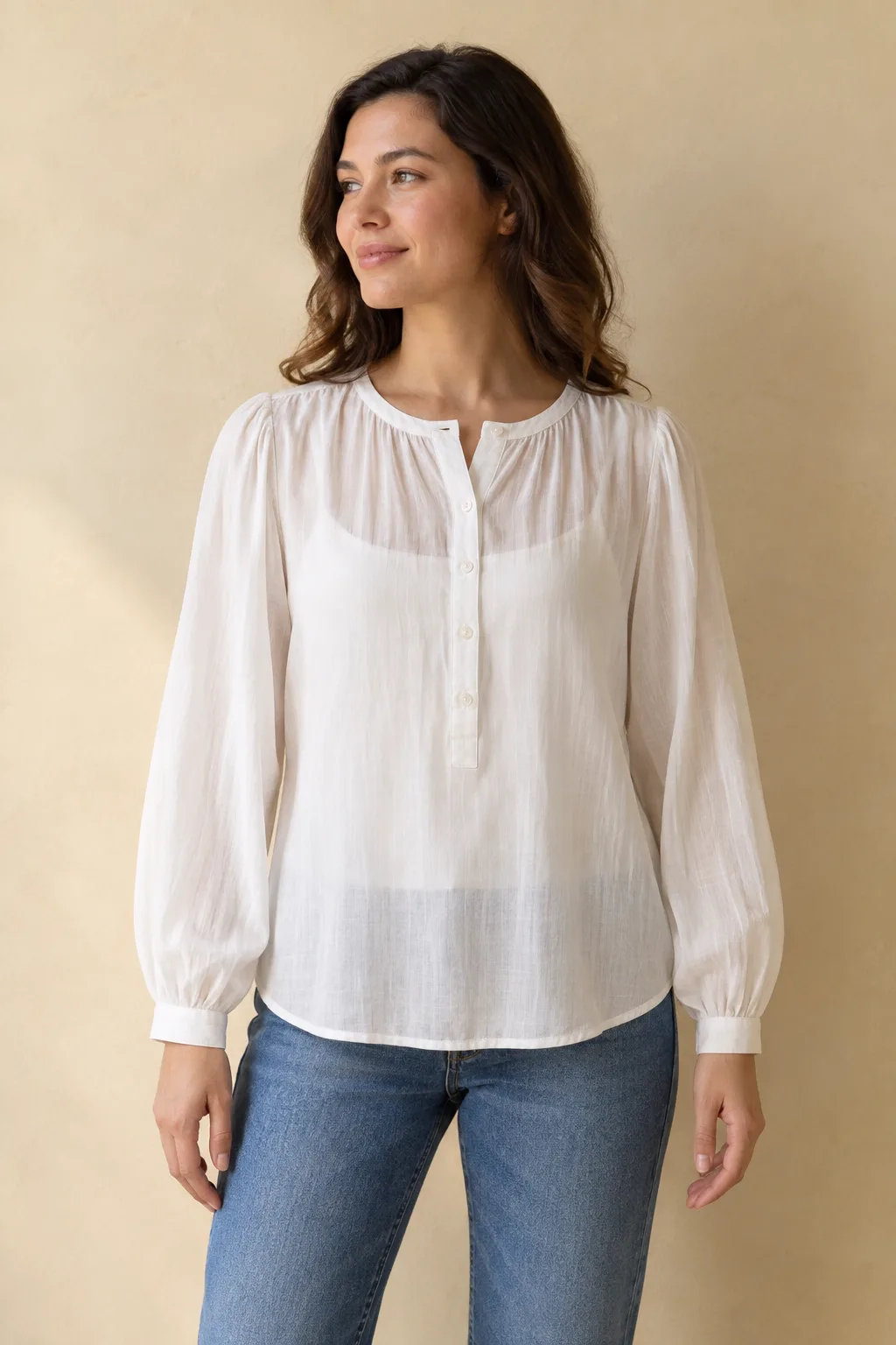 Warm-white cotton voile blouse with gathered sleeves, worn over a separate camisole